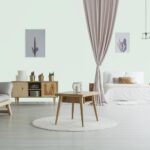 Spacious living room with wooden table on white carpet, rustic cupboard and grey sofa near open bedroom